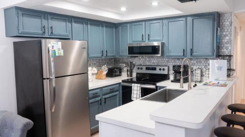 a kitchen with blue cabinets and a stainless steel refrigerator at Walkable Location - 99 Steps to Beach - Pool in South Padre Island