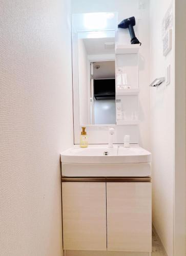 a bathroom with a white sink and a mirror at Hotel Arashi Tengachaya No005 in Osaka