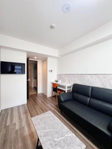 a living room with a black couch and a table at Hotel Arashi Tengachaya No005 in Osaka
