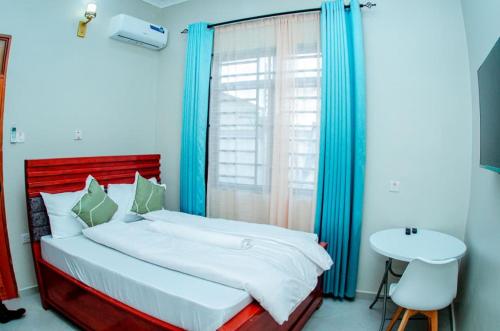 a bedroom with a bed and a table and a window at Kibs Apartments in Dodoma