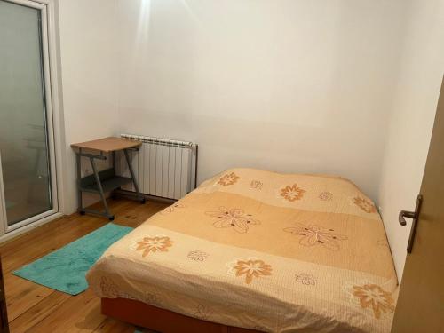 a small bedroom with a bed and a table at Apartman Buric in Vogošća