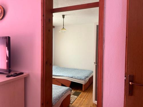 a room with two beds in a room with pink walls at Apartman Buric in Vogošća