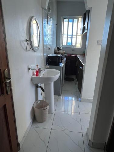 a white bathroom with a sink and a mirror at Skyview Bamburi Suites in Mombasa