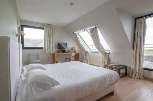 a bedroom with a white bed and two windows at Logis Le Château de Sable in Porspoder