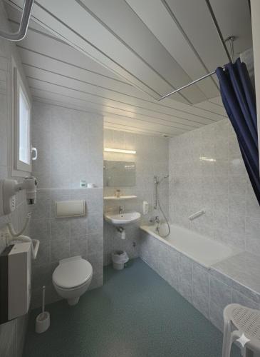 a bathroom with a toilet and a tub and a sink at Hôtel Myosotis in Lourdes