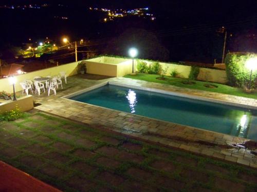 a swimming pool at night with a table and chairs at Casa da Vó Lucia in Serra Negra