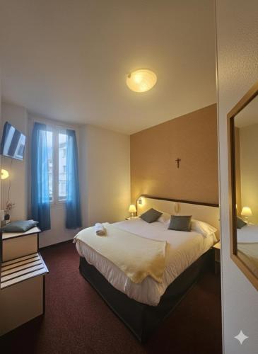 a hotel room with a large bed and a window at Hôtel Myosotis in Lourdes