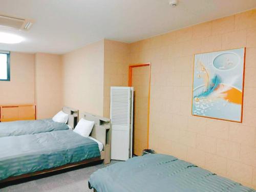 a bedroom with two beds and a painting on the wall at ゲストハウス瓦町 in Takamatsu