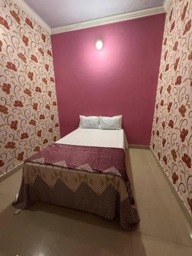 a small bed in a room with a purple wall at Karuna Homestay in Ujjain