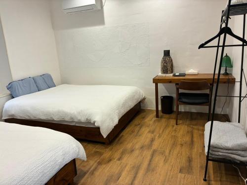 a bedroom with two beds and a desk with a table at Cottage Tasuki in Nakijin