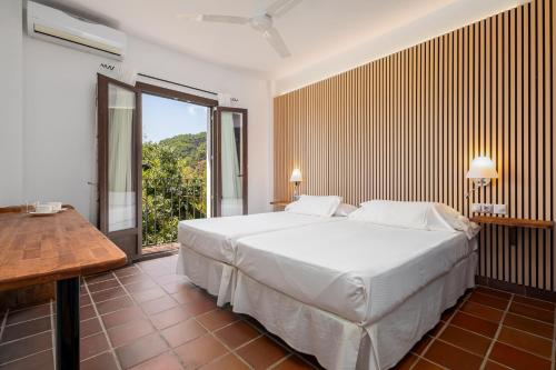 a bedroom with a large white bed and a window at Cerro de Hijar in Tolox