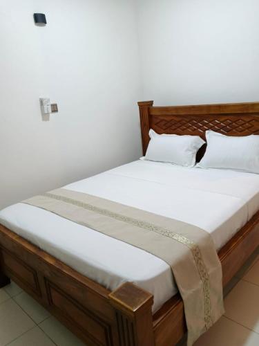 a bed with white sheets and pillows in a room at Bluu Diani in Diani Beach