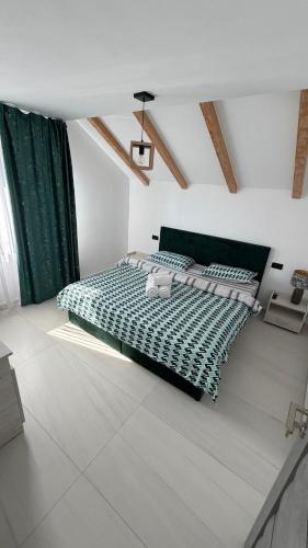a bedroom with a bed with a green comforter at Casa Blanca in Caransebeş