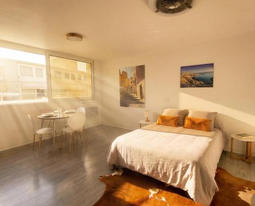 a bedroom with a bed and a table with chairs at Studio Les Allées in LʼÎle-Rousse