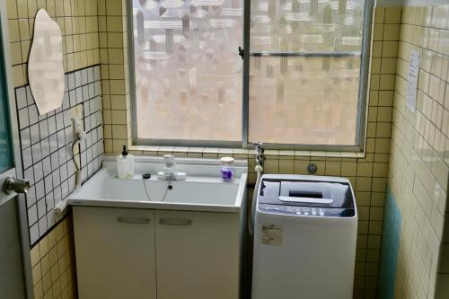 a small bathroom with a sink and a window at 一棟貸しの宿 Granny and the sea グラニーアンドザシー in Shima