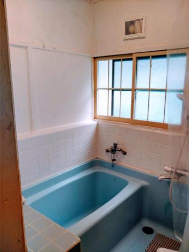 a blue tub in a bathroom with a window at 101個室元芸者の隠れ宿湯河原 in Yugawara