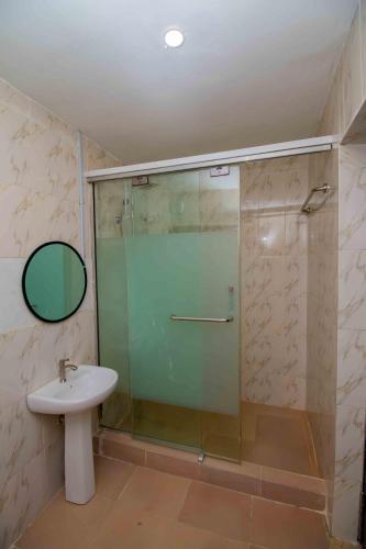 a bathroom with a glass shower and a sink at Living Space Apartment in Ibadan