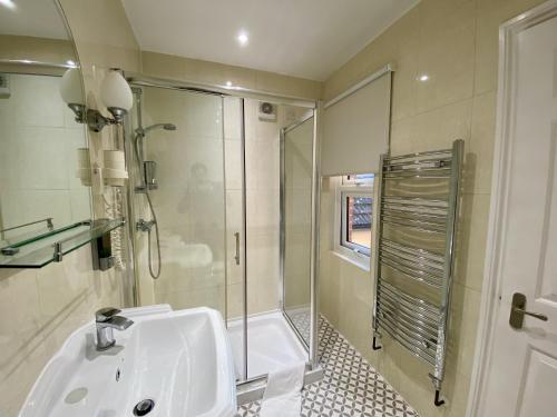 a white bathroom with a shower and a sink at Pickwicks Guest House in Oxford