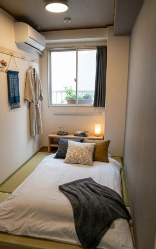 a large bed in a room with a window at 心斎橋難波関空直通 Ambers Hostel in Osaka