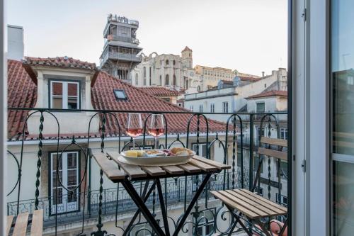 a table with wine glasses and a bowl of food on a balcony at Ando Living - Santa Justa 79 House in Lisbon