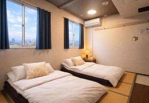 two beds in a room with two windows at 心斎橋難波関空直通Nambaminami direct to Shinsaibashi Ambers Hostel in Osaka