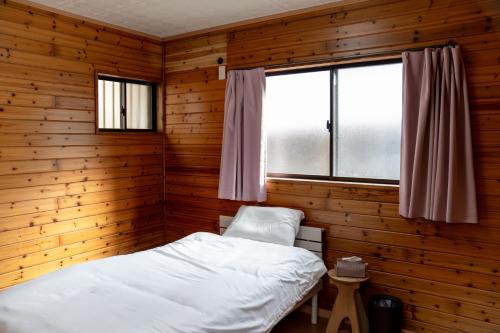 a room with a bed in a wooden room with a window at 一棟貸しの宿 Granny and the sea グラニーアンドザシー in Shima