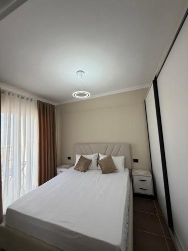 a bedroom with a white bed and a window at Rapo Apartment in Krujë
