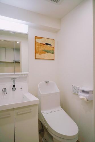 a white bathroom with a toilet and a sink at Sky Home新宿 in Tokyo
