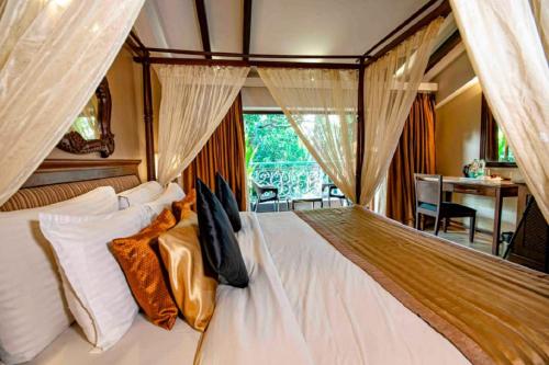 a bedroom with a large white bed with curtains at Tangerine Boutique Resort in Calangute