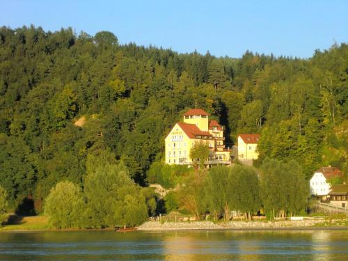 a house on a hill next to a body of water at Hotel-Restaurant Faustschlössl in Feldkirchen an der Donau