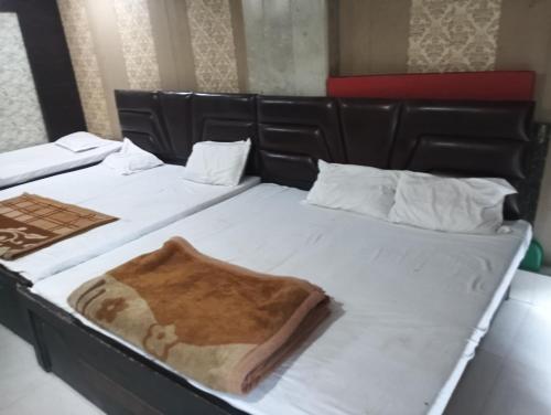 two beds with white sheets and a brown blanket at Shri Krishna Guest House in Mathura