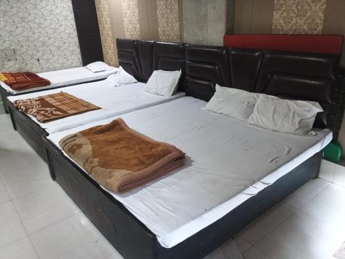 two beds with white sheets and a blanket on them at Shri Krishna Guest House in Mathura