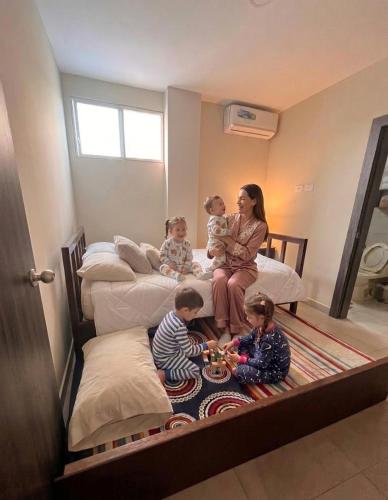 a woman and three children sitting on beds at departamento Vacacional, frente al mar in Playas