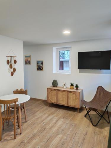 a living room with a table and a tv on a wall at Roger's appartement in Larrivière