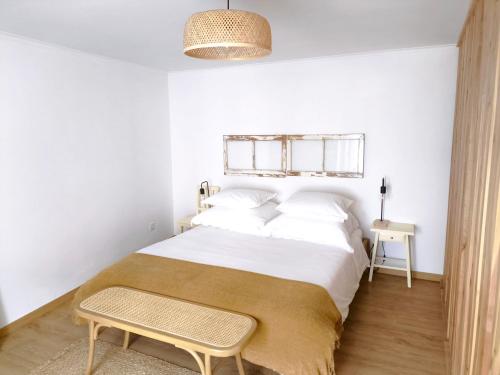 a bedroom with a large bed with white sheets and a table at O Refúgio do Pim in Horta