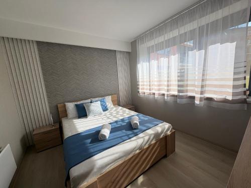 a bedroom with a bed with blue sheets and a window at BL Residence Balatonlelle in Balatonlelle