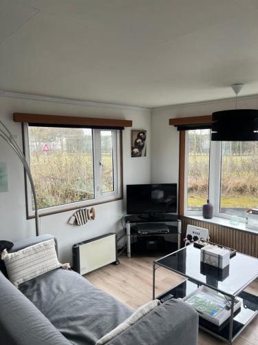 a living room with a couch and a glass table at Chalet Inn Ameland inclusief Fietsen, Zee en Strand op loopafstand! in Buren