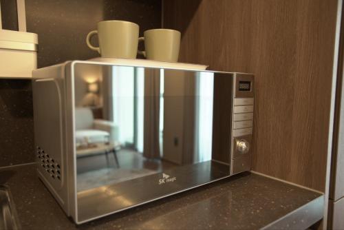 a microwave oven with two cups on top of it at Sienna Ambassador Residence in Busan