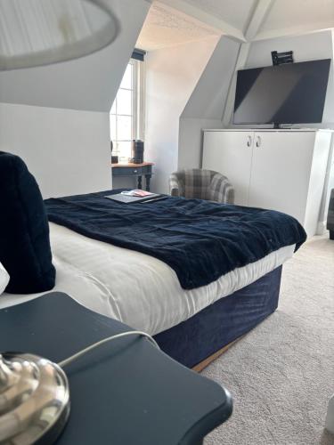 a bedroom with a large bed with a black blanket at Navigator Hotel in Bognor Regis