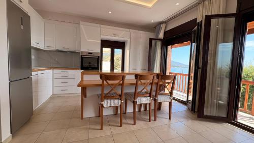 a kitchen with a table and chairs and a balcony at Kỳma - Stone Luxury Villa in Órmos Koumaíïkon