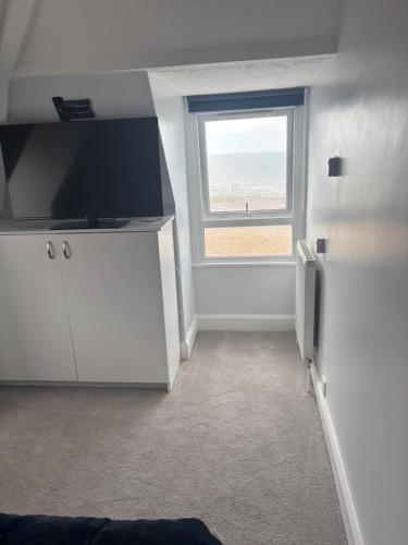 a room with a television and a window with the beach at Navigator Hotel in Bognor Regis