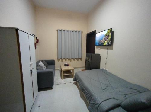 a bedroom with a bed and a couch and a television at comfort stay 1 in Al Ain