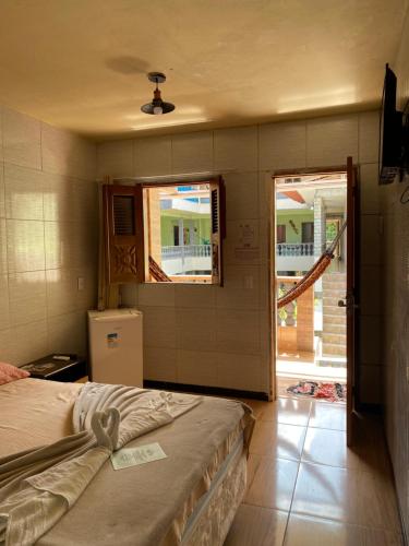 a bedroom with a bed and two windows and a refrigerator at Pousada Preocupacao Zero in Ubajara