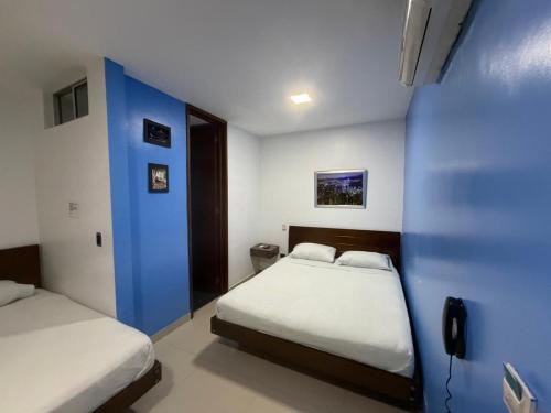 a bedroom with two beds and a blue wall at Hotel Suites Caribe in Barranquilla