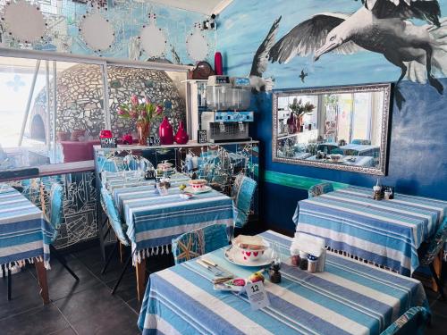 a restaurant with blue and white tables and a bird mural at Cape Nomads in Muizenberg