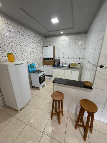 a kitchen with two stools and a table and a refrigerator at Casa Ibirapuera in Vitória da Conquista