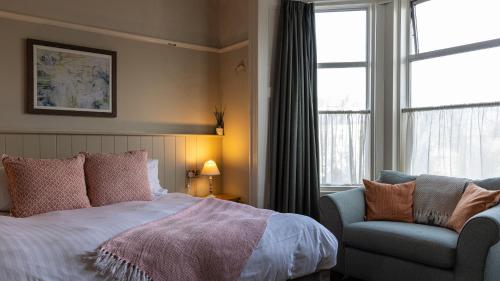 a bedroom with a bed and a chair and a window at Burrator Inn in Yelverton