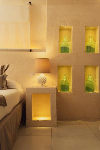 a bedroom with green bottles on the wall at Masseria Messapia Wine Resort & Spa Salento in Mesagne
