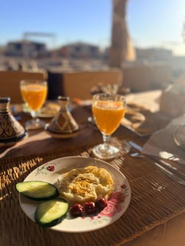 a table with a plate of food and glasses of orange juice at Rimal tata camp in Migourdâne