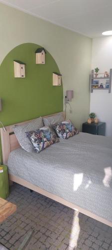 a bedroom with a large bed with a green wall at Biesbosch Bed & Breakfast Werkendam in Werkendam